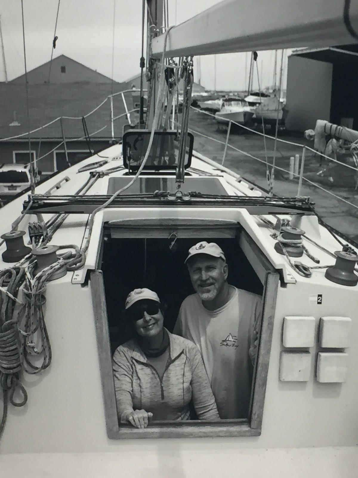 Two people smiling in a sailboat cabin on a dock.