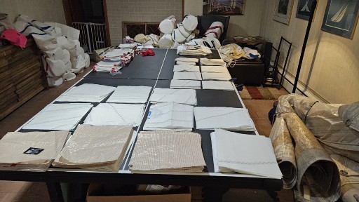 A table covered with neatly folded white and beige fabric pieces.