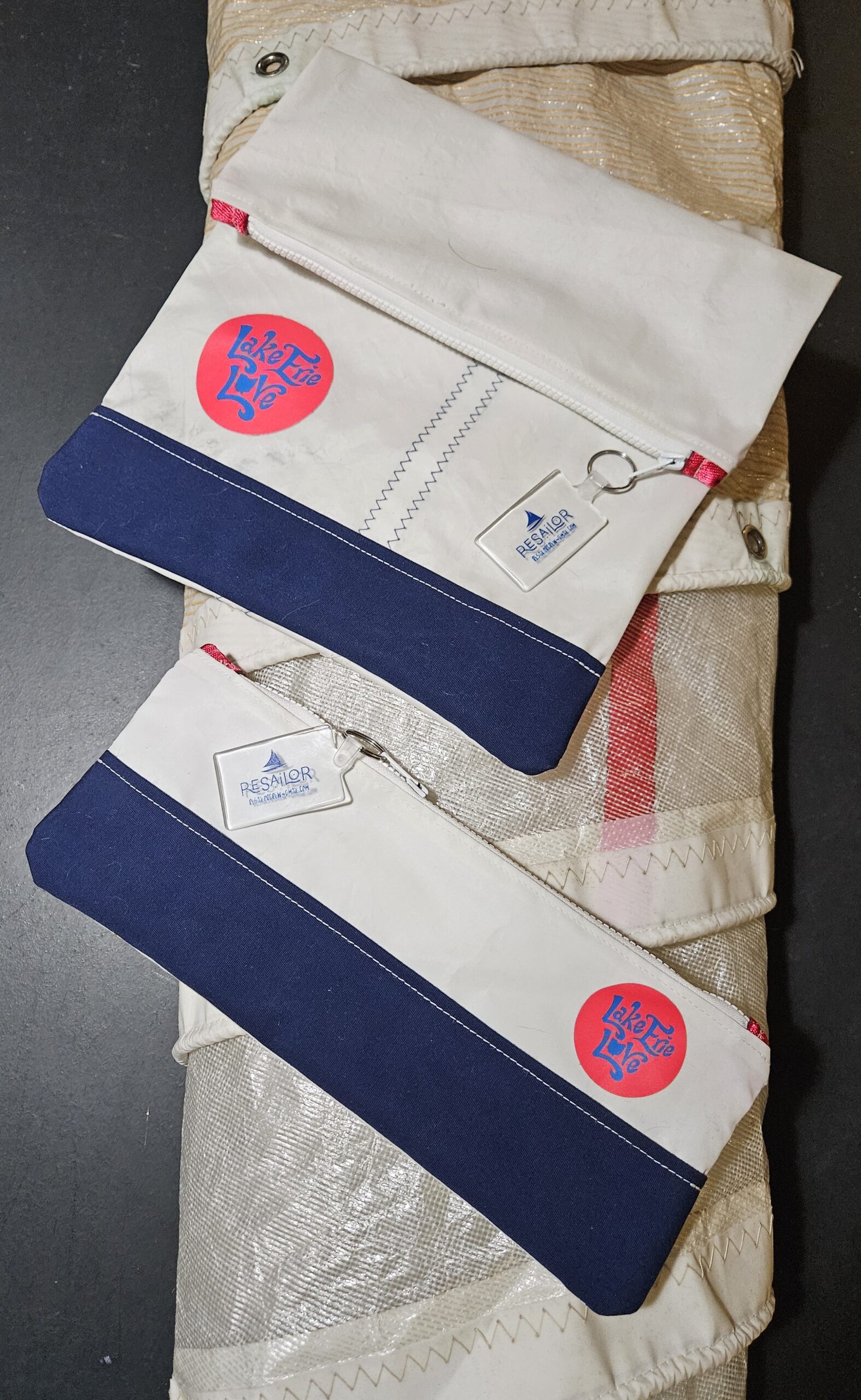 Two white and navy blue pencil cases with red circular patches and tags.