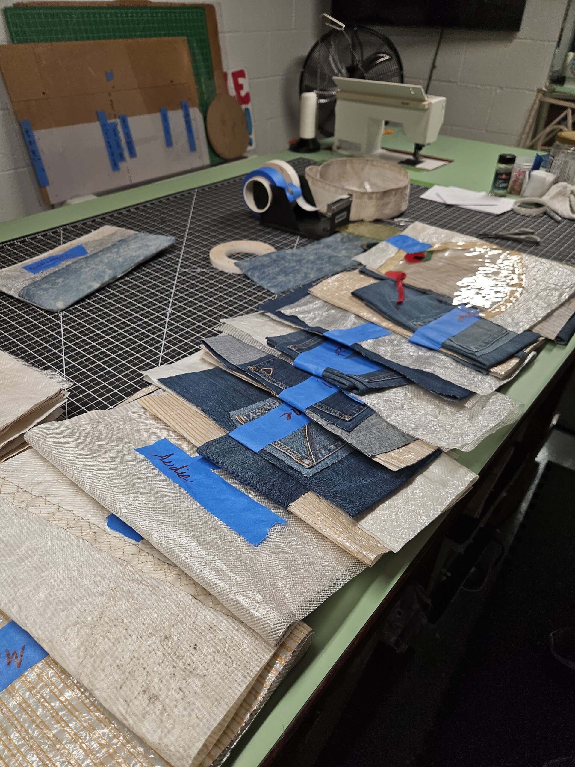 A row of golf club heads being refinished with blue tape on a workbench.