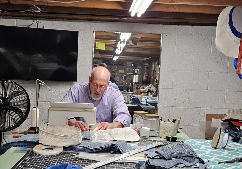 Man working intently on a sewing machine in a workshop.